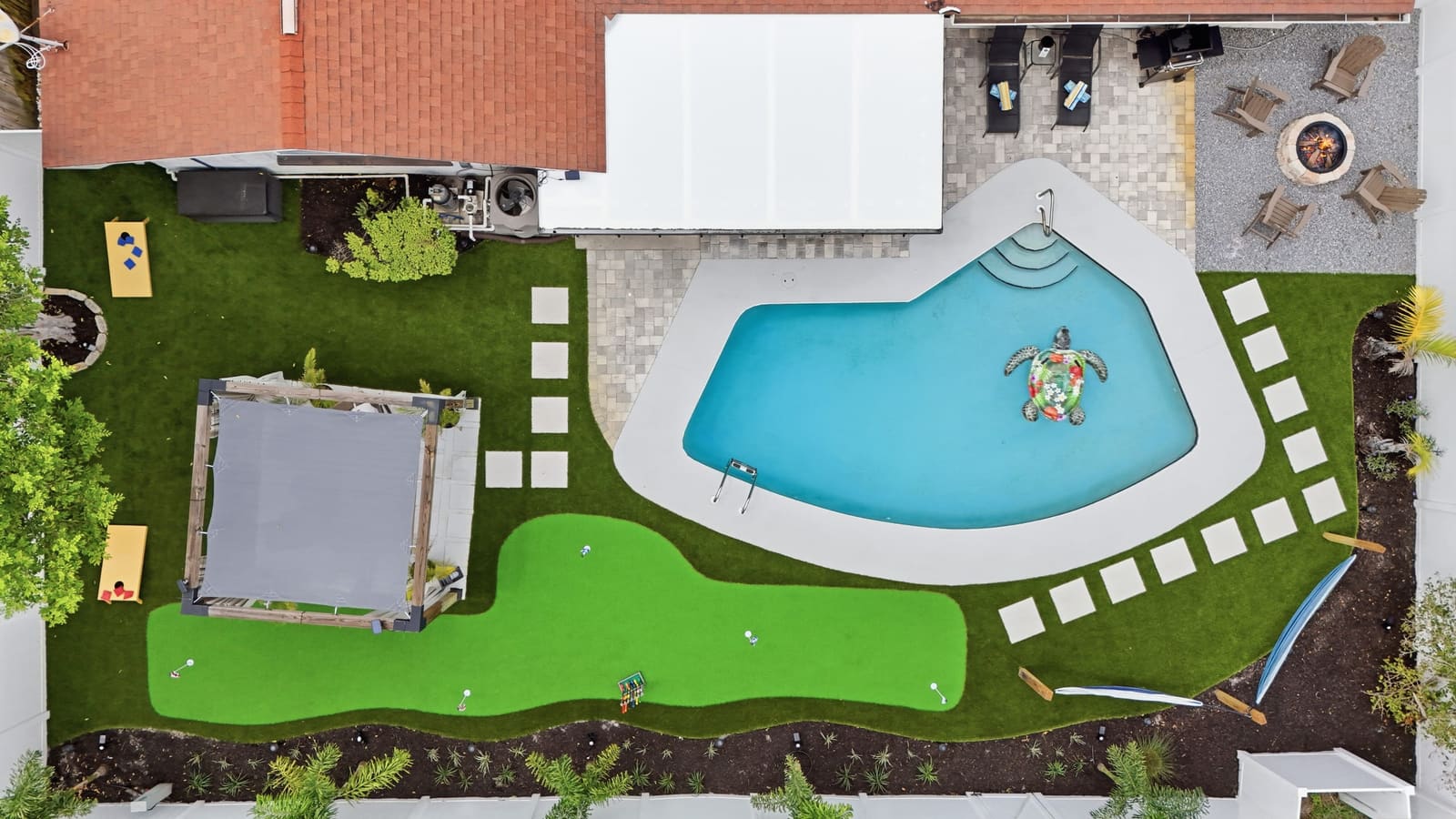The whole back yard photographed from directly overhead: pool, putting green, pergola and fire pit.