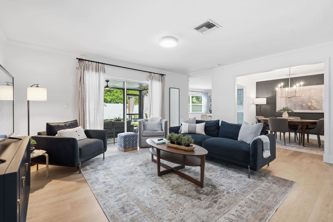 The living room of the vacation rental, navy sofa and oval coffee table, with the dining room through the opening.