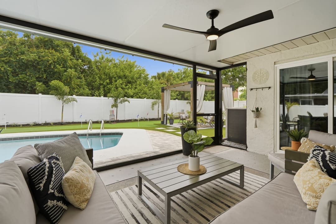 The screened lanai looking out at the pool and putting green through the black-framed screen wall.